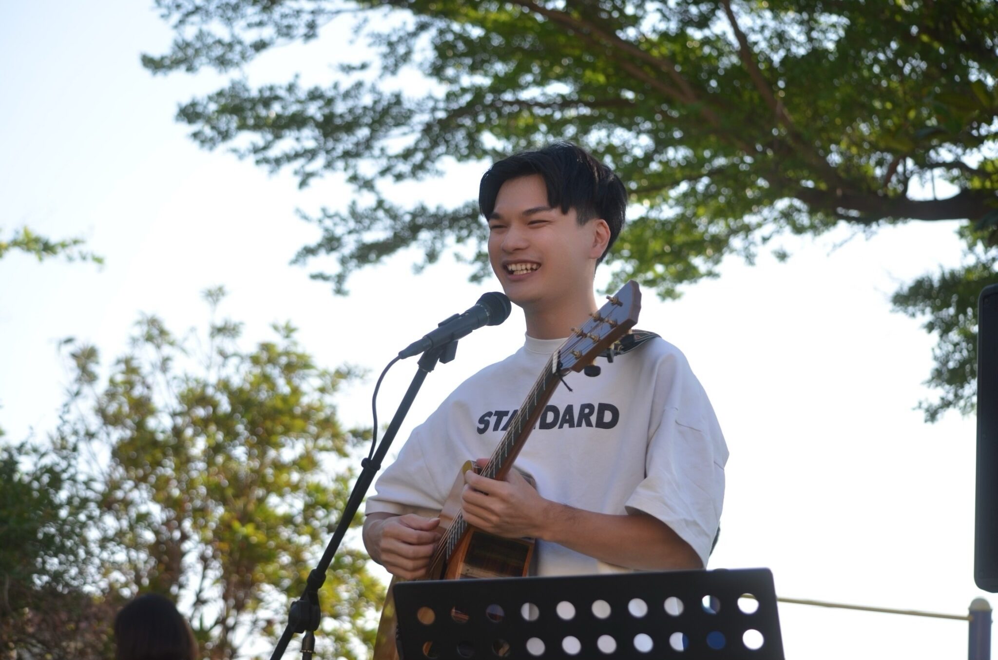 手持麥克風於戶外草地演奏吉他彈唱